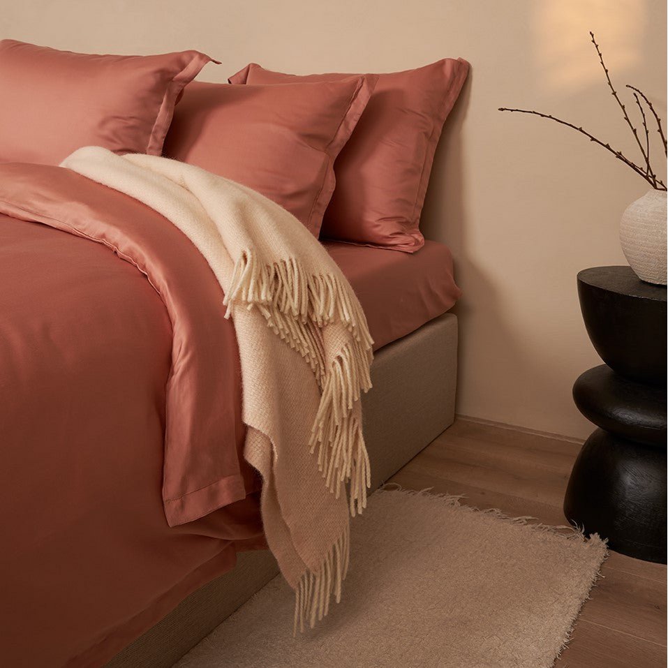 Alpaca Merino Throw Blanket draped over a bed with terracotta bedding