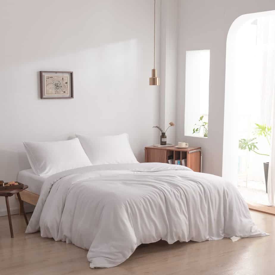 White bamboo duvet cover in Coco White styled on a bed in a bright, modern bedroom with wood floors and a hanging pendant light