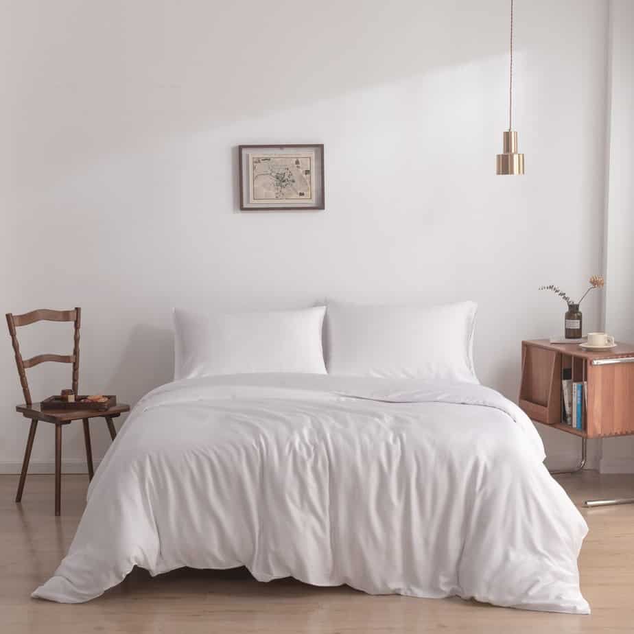 Bamboo duvet cover in Coco White on a bed beside a wooden chair and side table in a minimalist bedroom