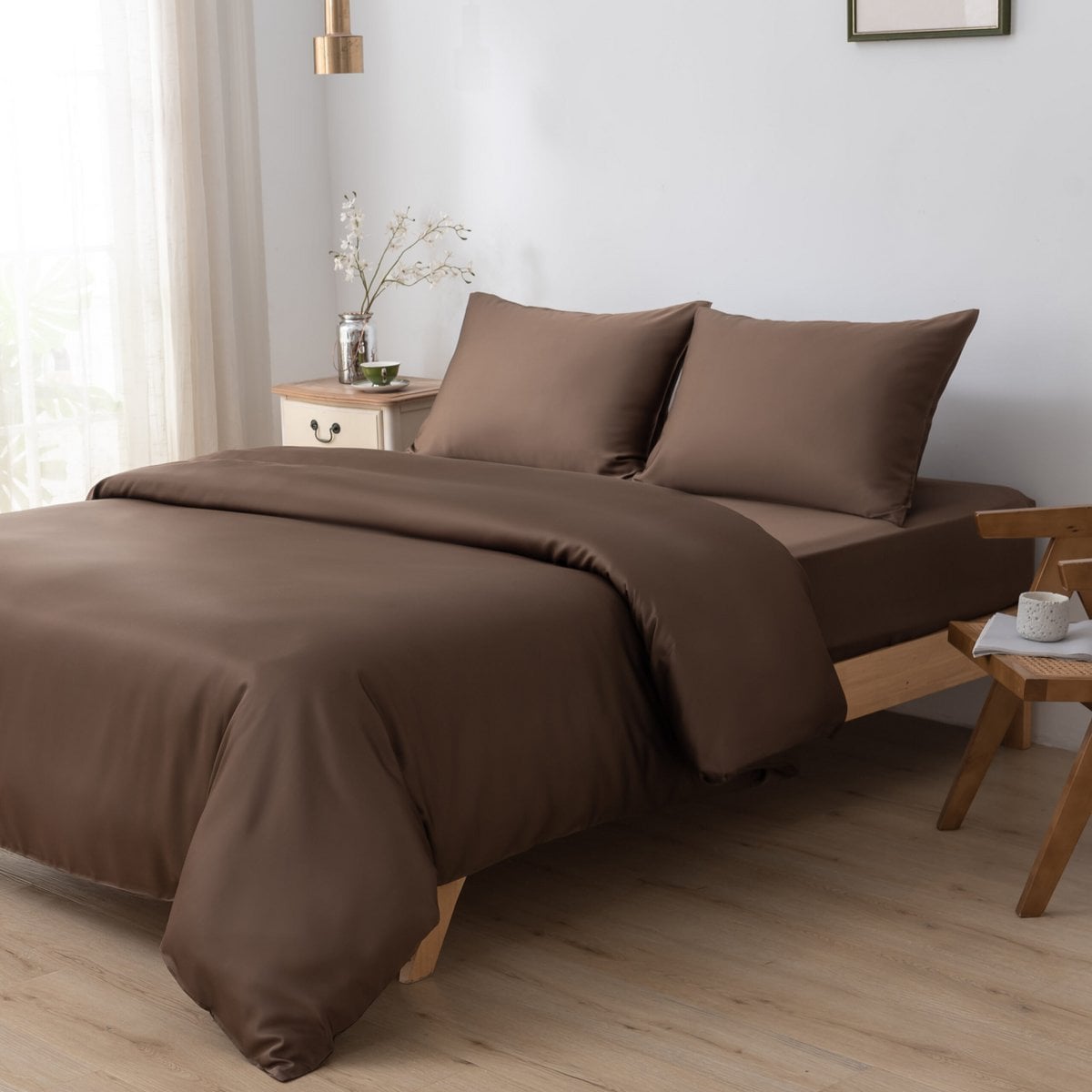 Bamboo duvet cover in Coffee Brown on a bed beside a cane chair with a cup