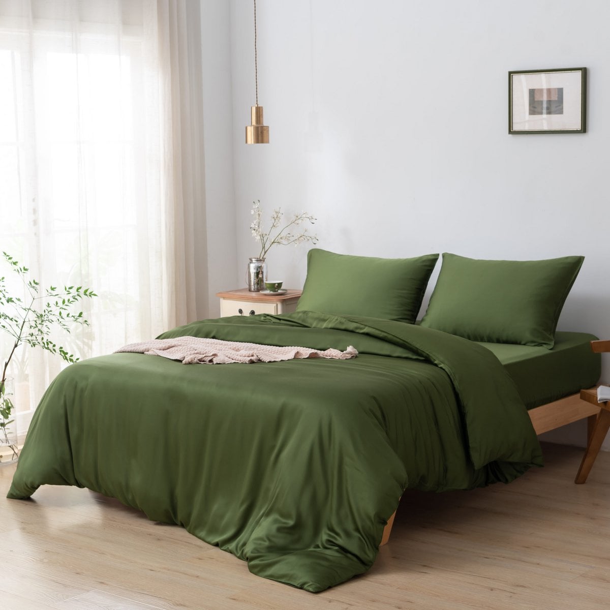 Bamboo duvet cover in Deep Moss styled on a bed with a hanging pendant light and framed art