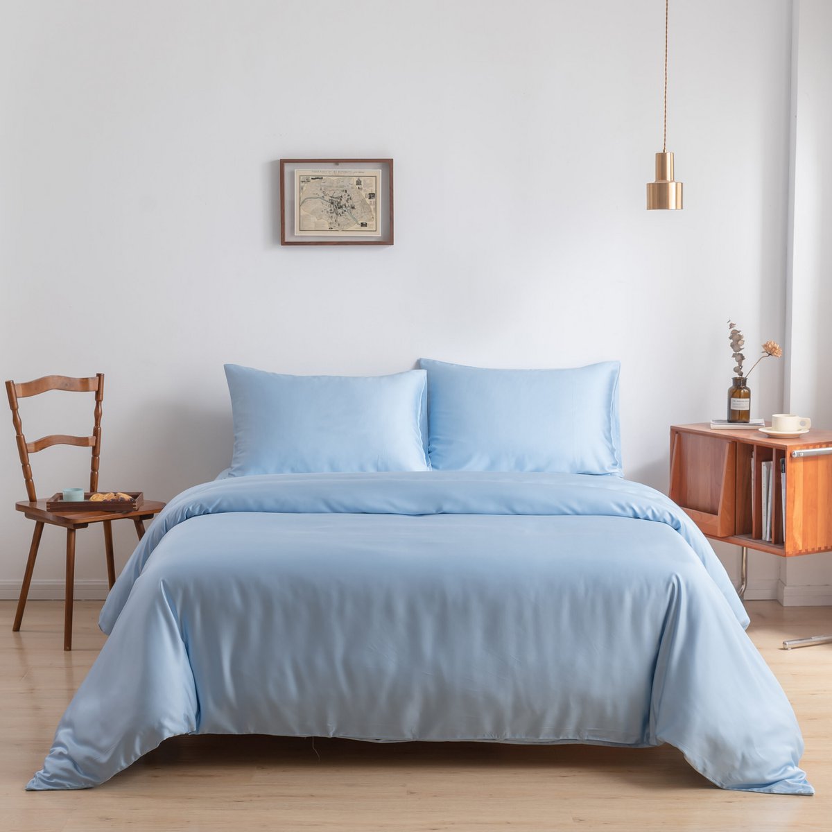 Bamboo duvet cover in Sky Blue on a bed with a framed map on the wall and a wooden nightstand