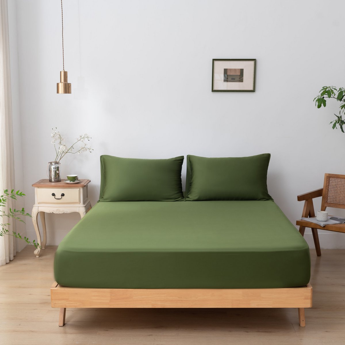Deep Moss bamboo fitted sheet on a made bed, shown straight-on with two matching pillows.