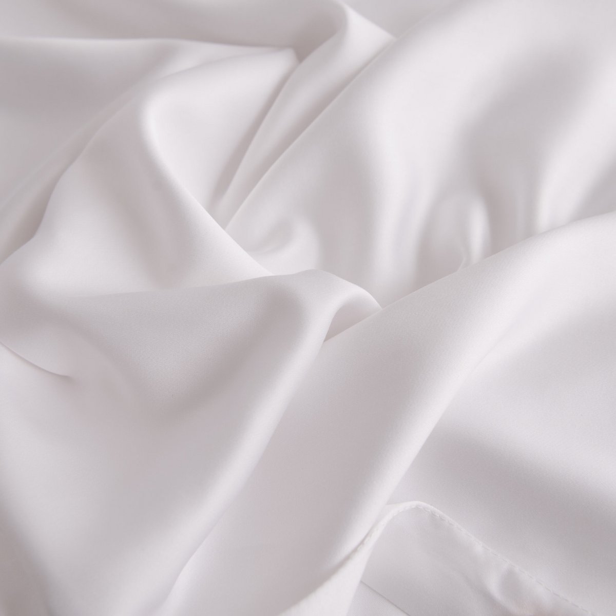 Close-up of draped Coco White bamboo fabric showing its smooth, silky texture.