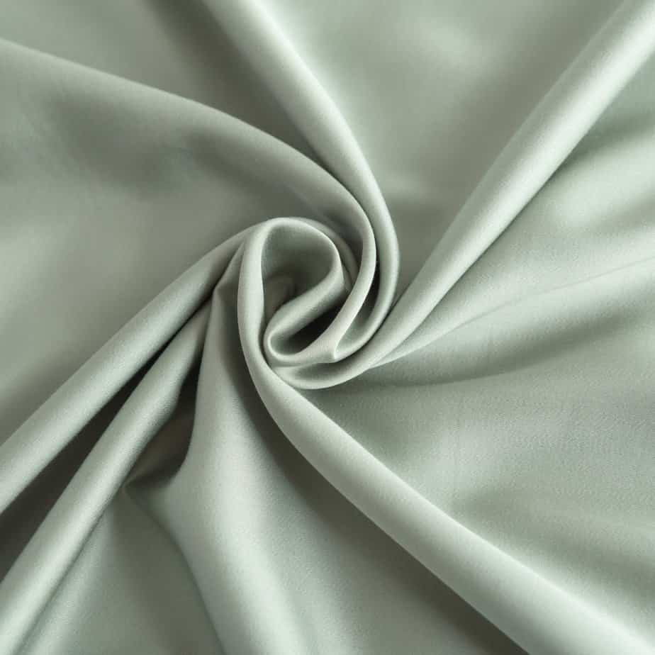 Close-up of swirled Sage Green bamboo fabric showing its smooth, silky texture.