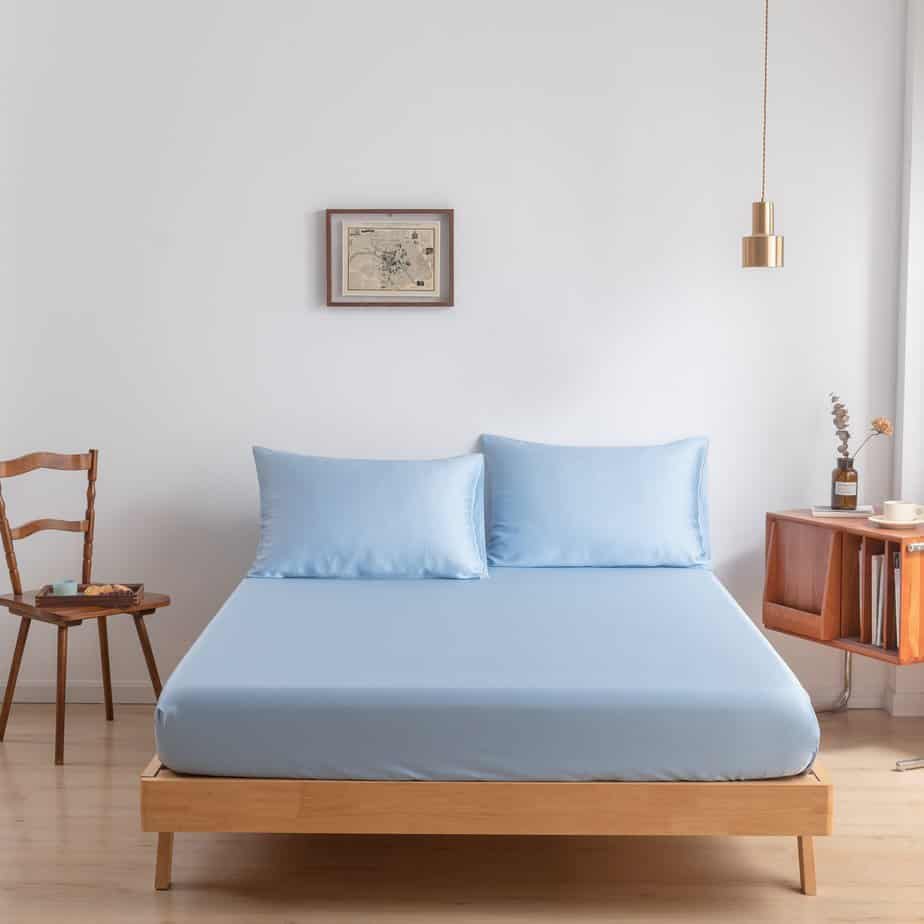 Sky Blue bamboo fitted sheet styled on a wood-frame bed beside a wooden chair.