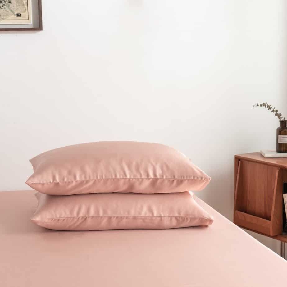 Cuddle Pink bamboo pillowcases styled on a bench in a bedroom setting