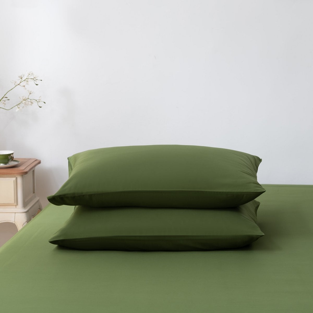 Deep Moss bamboo pillowcases styled on a made bed