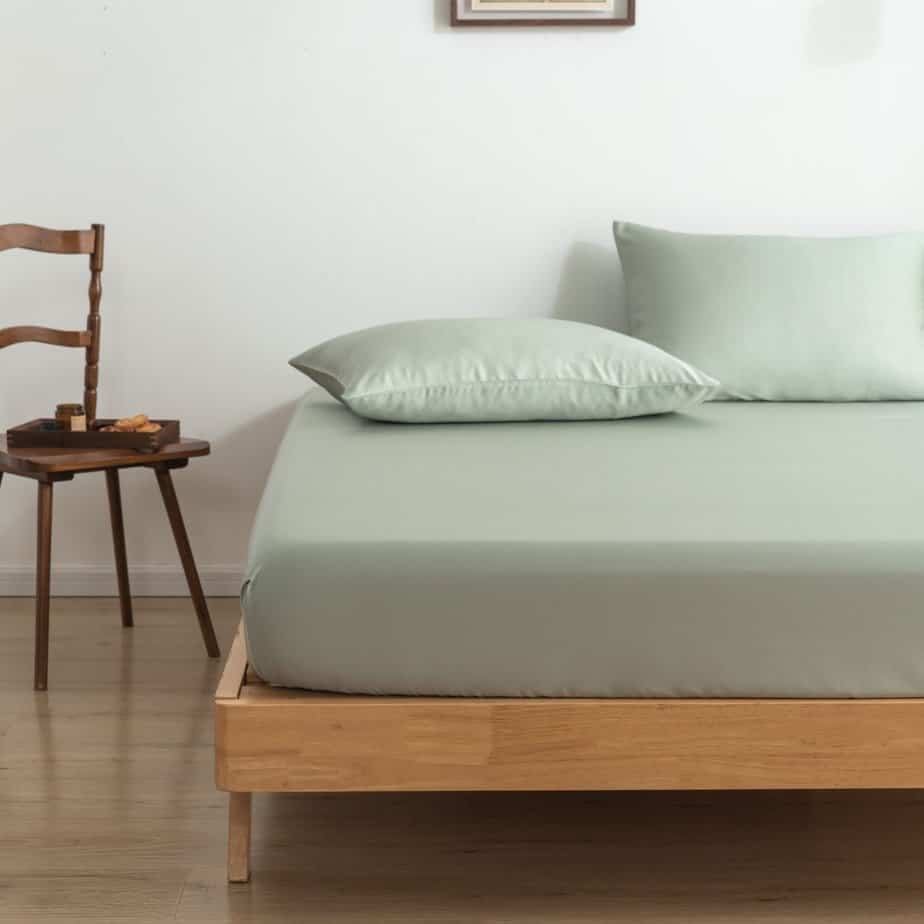 Sage Green bamboo pillowcases on a wood-framed bed