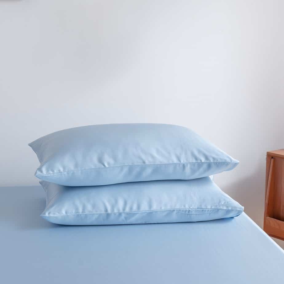 Sky Blue bamboo pillowcases styled on a bench in a bedroom setting