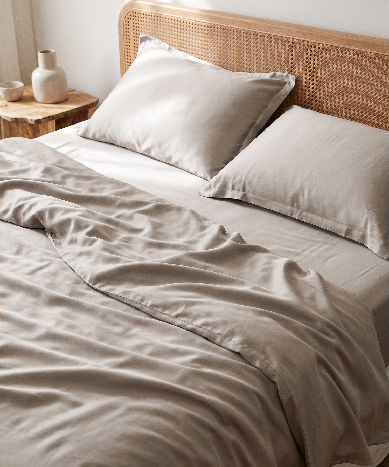 Silky taupe TENCEL & Lyocell bedding on a bed with a rattan headboard