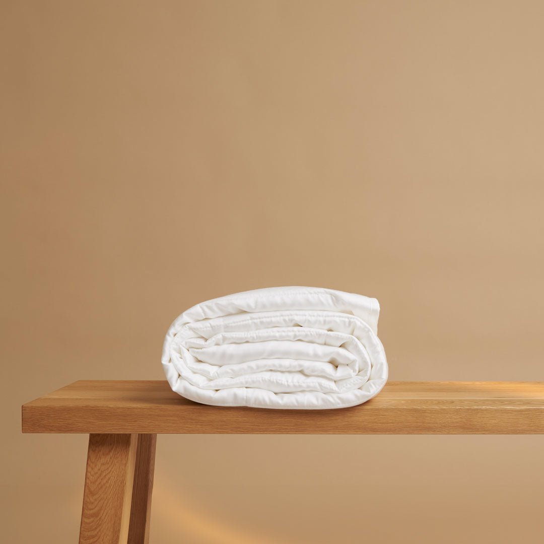 Tencel™ High Summer Duvet, rolled and folded on a wooden bench