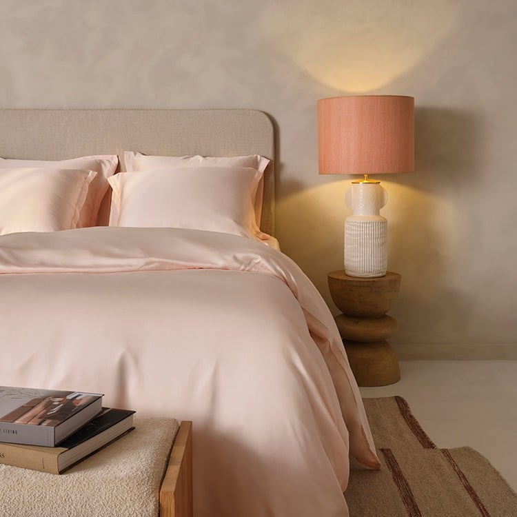 Tencel™ Sateen Duvet Cover in Peach White styled on a bed with warm lighting