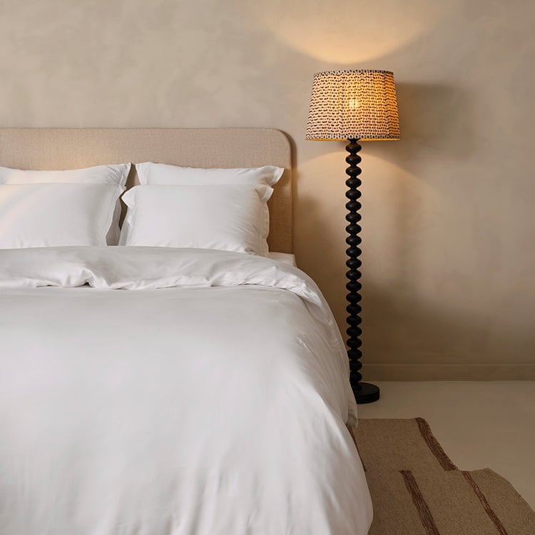 Tencel™ Sateen Duvet Cover in White styled on a bed with a floor lamp