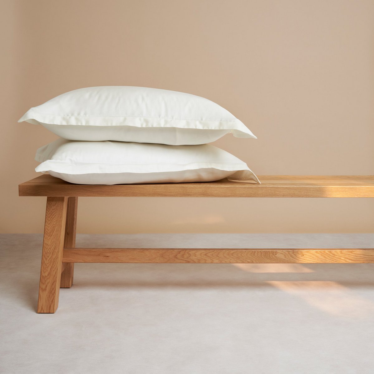 Tencel Sateen pillowcases in off white styled on a wooden bench