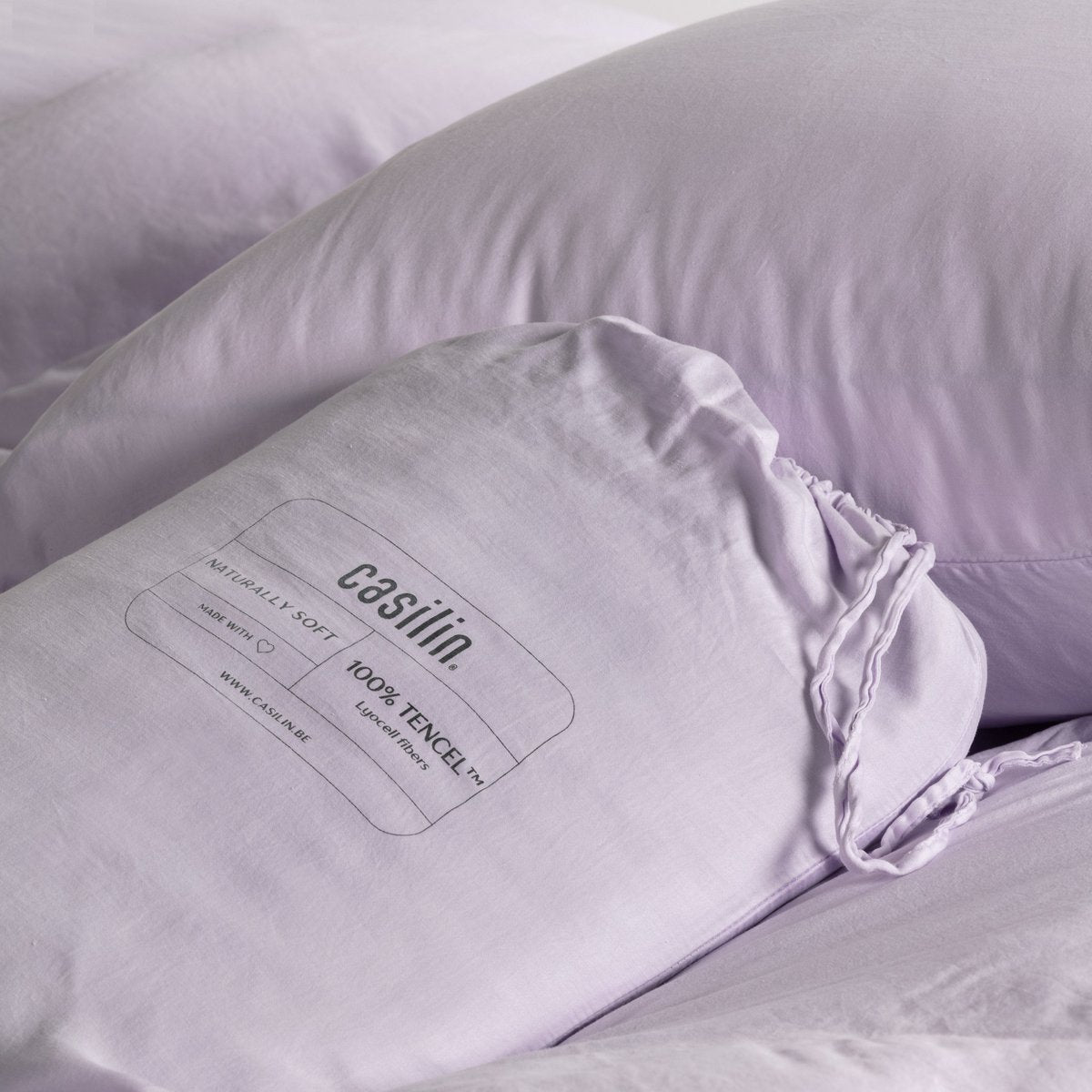 Close-up of the Casilin fabric label on the lilac duvet cover showing the bottle-neck closure and 100% Tencel Lyocell fiber content