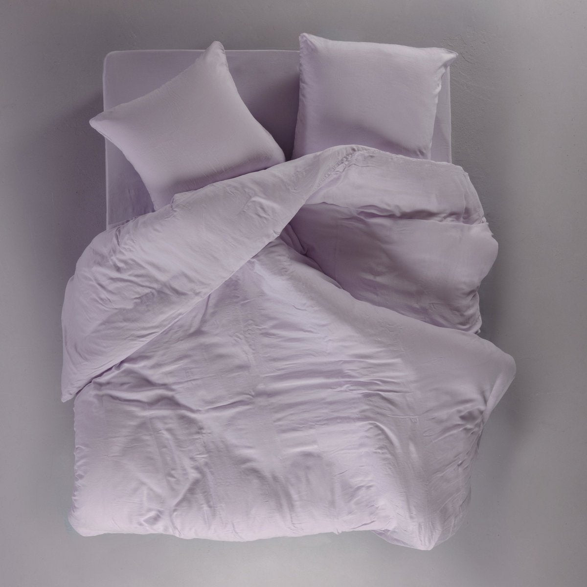 Overhead view of the lilac Tencel satin duvet cover and pillowcases styled on a bed