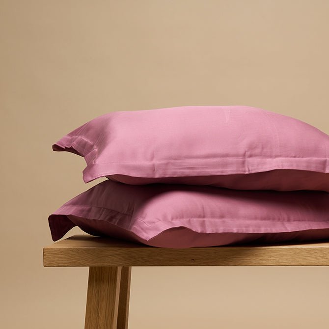 Tencel™ Twill Pillowcase in Dusty Rose stacked on a wooden bench