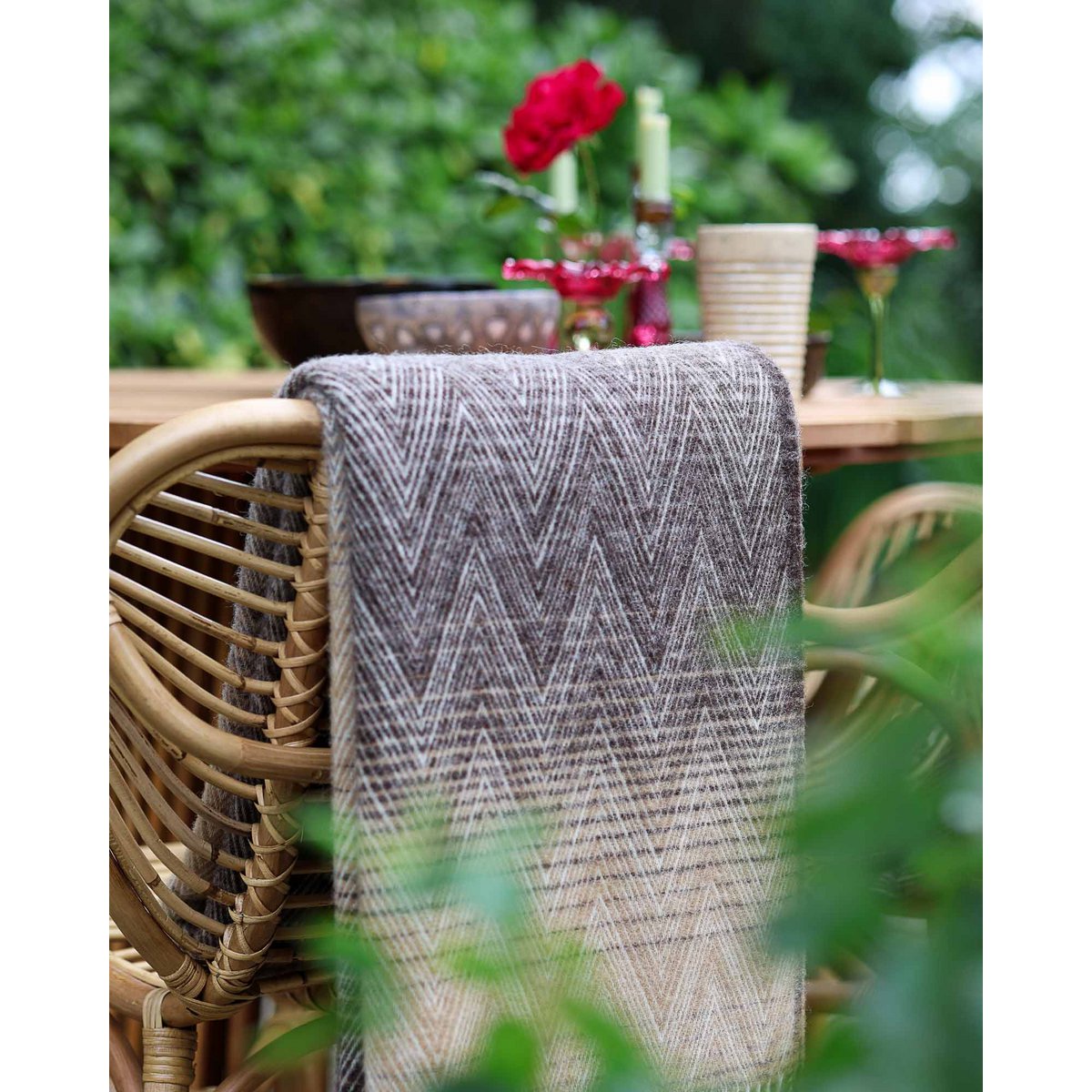 Wool Throw Blanket Manoria Savana draped over a wicker chair outdoors