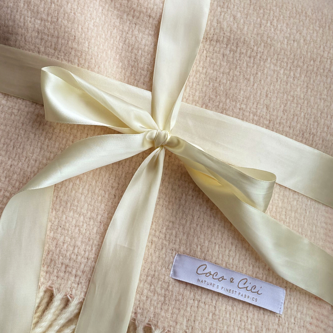 Close-up of the Alpaca Merino Throw Blanket's woven texture with a ribbon bow and Coco & Cici brand label