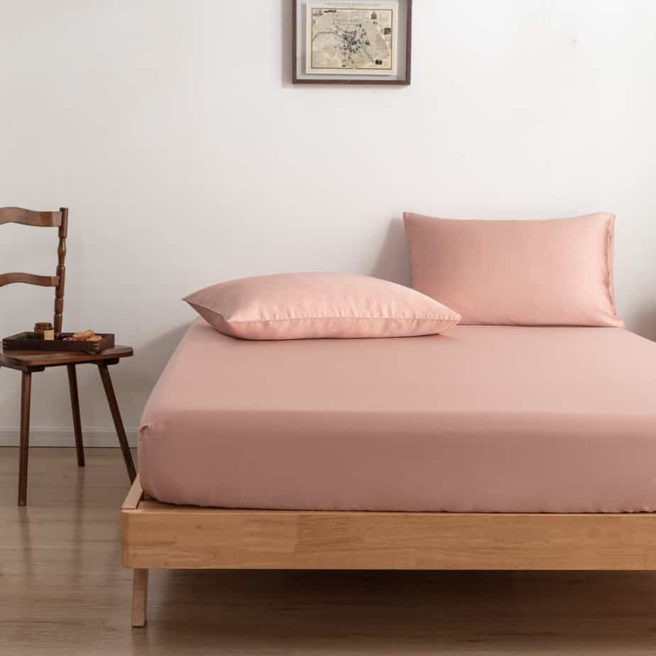 Cuddle Pink bamboo bedding set styled on a bed with a chair