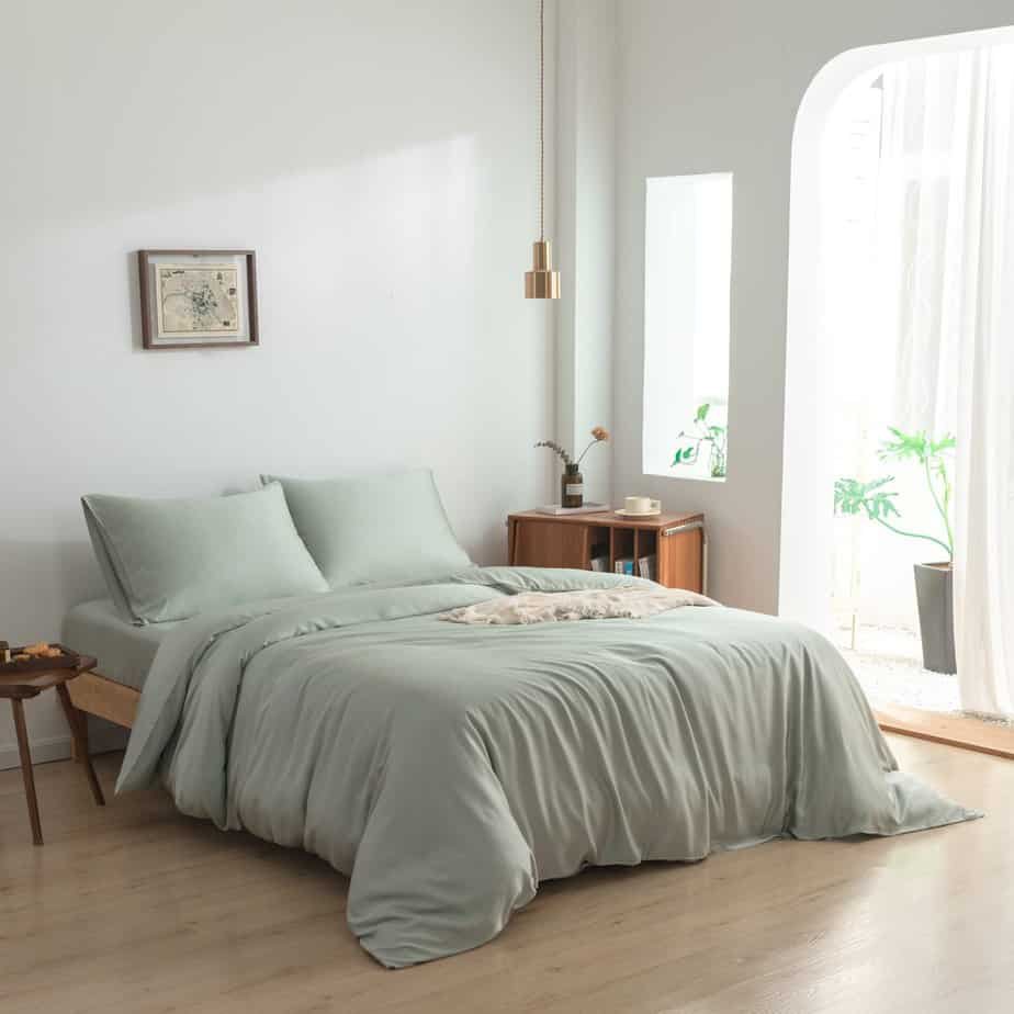 Sage Green bamboo bedding set styled on a bed by a window