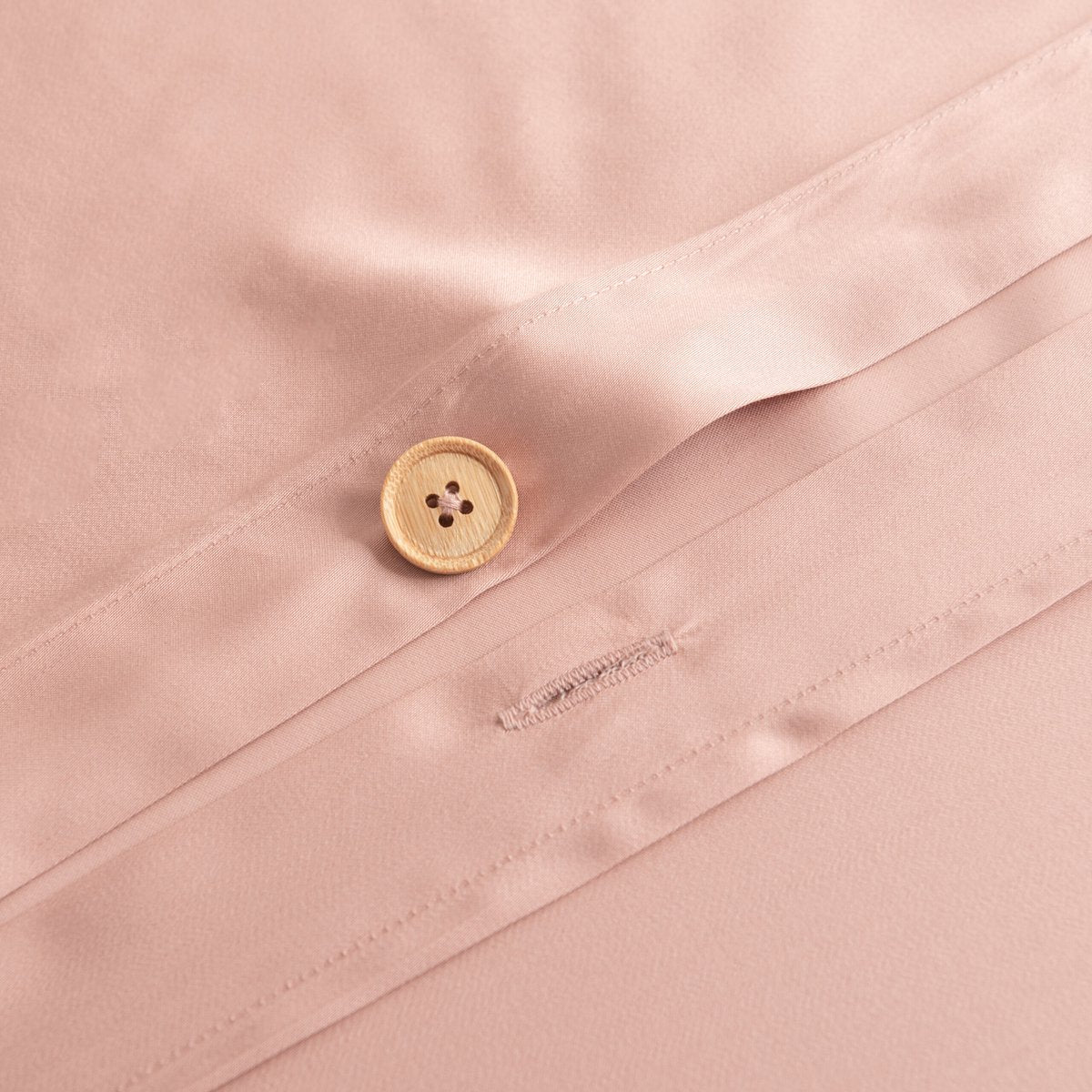 Close-up of a handmade bamboo button and buttonhole closure on the Cuddle Pink bamboo duvet cover