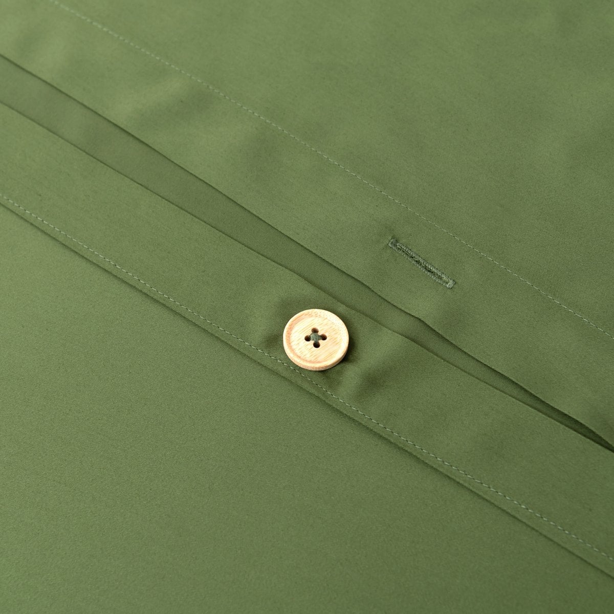 Close-up of a handmade bamboo button and buttonhole closure on the Deep Moss bamboo duvet cover