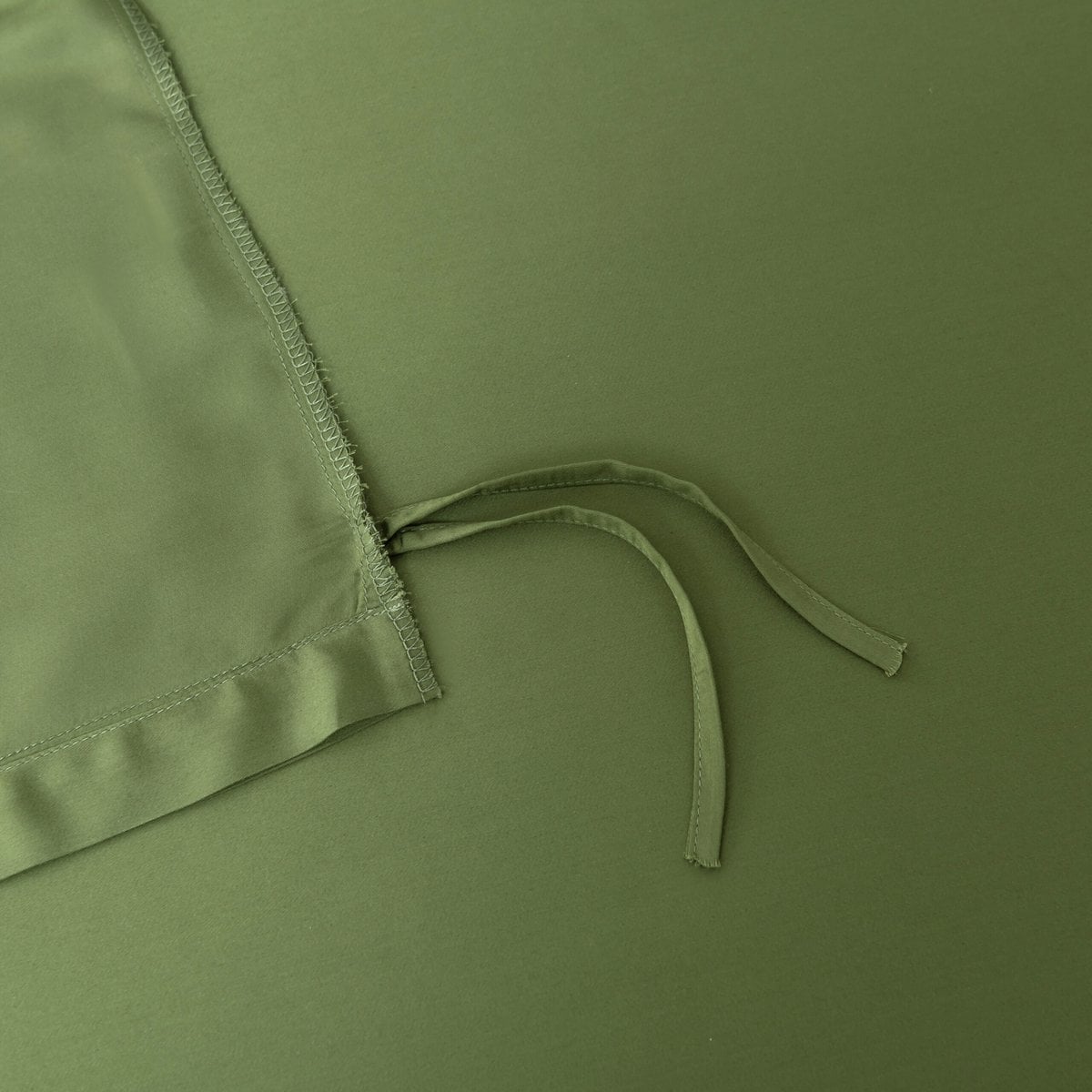 Close-up of the tuck-in strip ties on the corner of the Deep Moss bamboo duvet cover