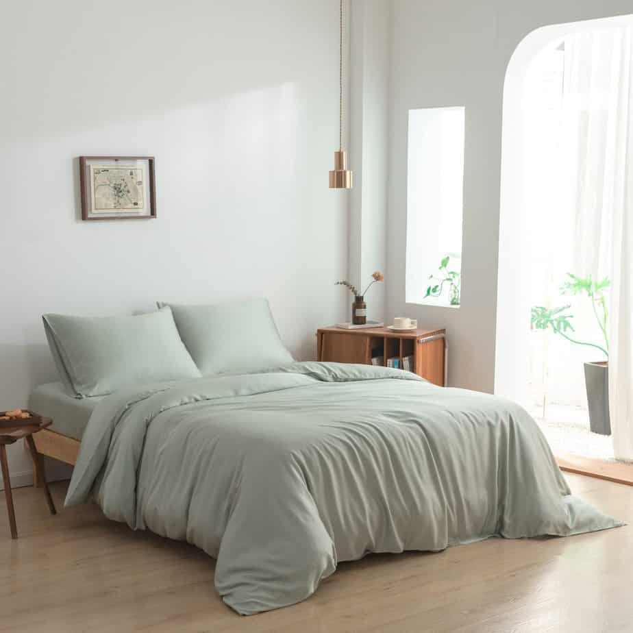 Bamboo duvet cover in Sage Green styled on a bed in a bright, modern bedroom with a hanging pendant light