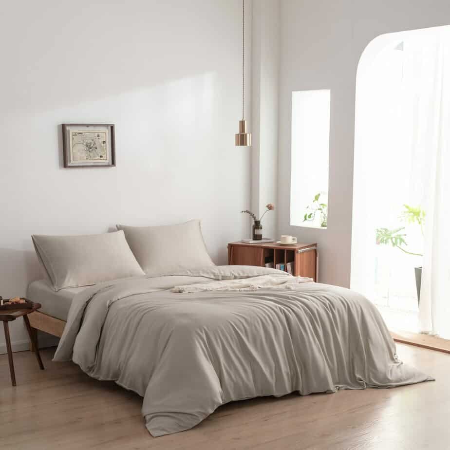 Bamboo duvet cover in Soft Taupe styled on a bed in a bright bedroom with a hanging pendant light and arched window