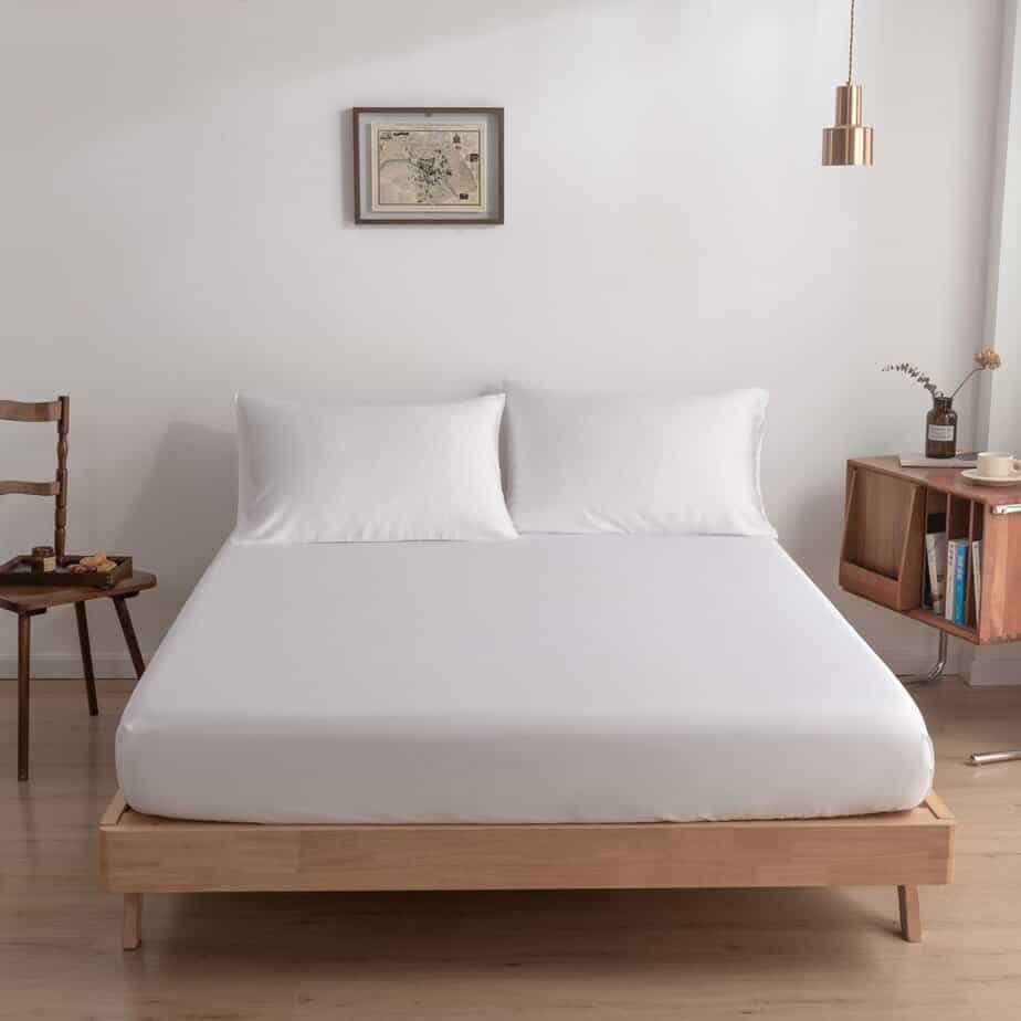 Coco White bamboo fitted sheet on a made bed, shown straight-on with two matching pillows.