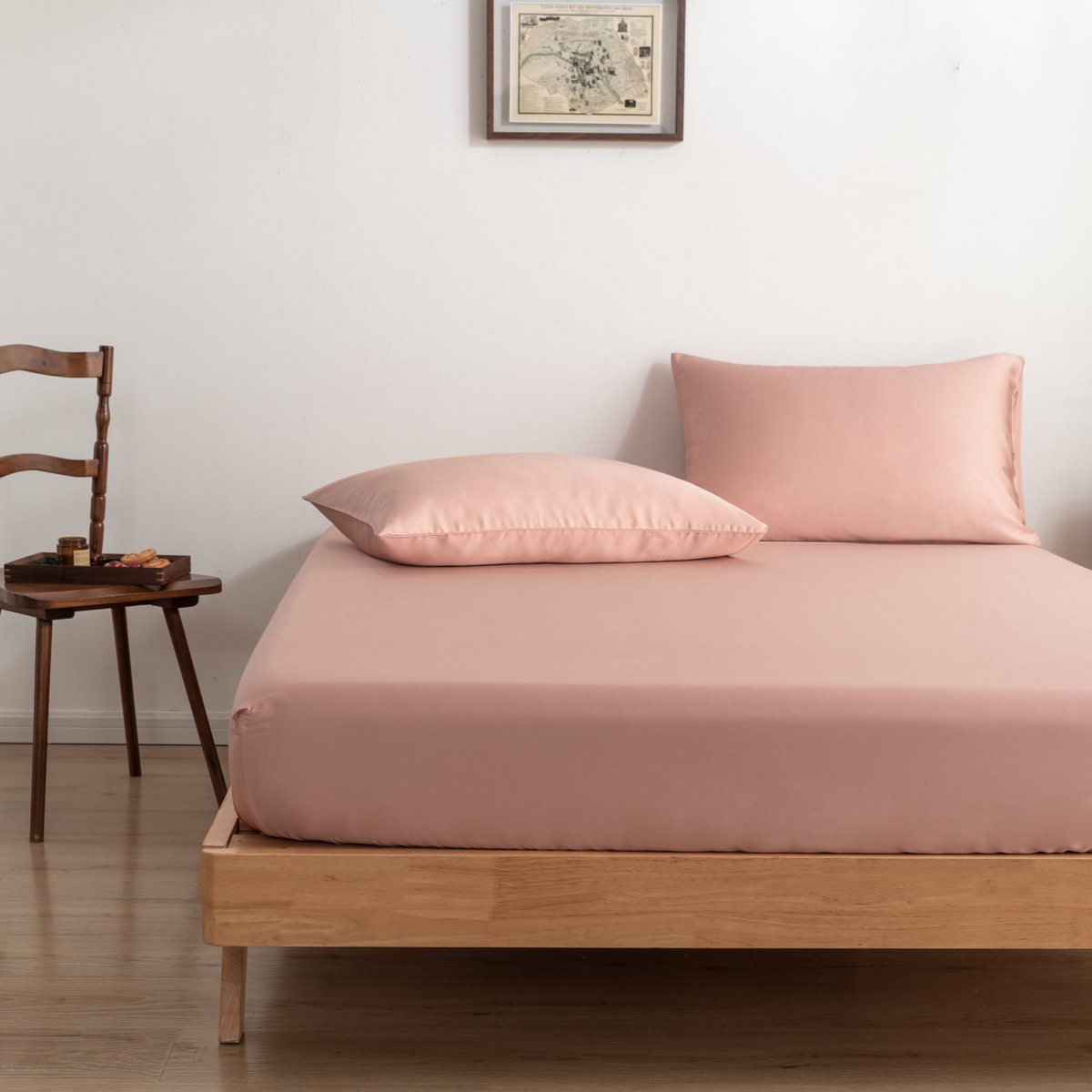 Cuddle Pink bamboo fitted sheet on a bed beside a wooden chair with a breakfast tray.