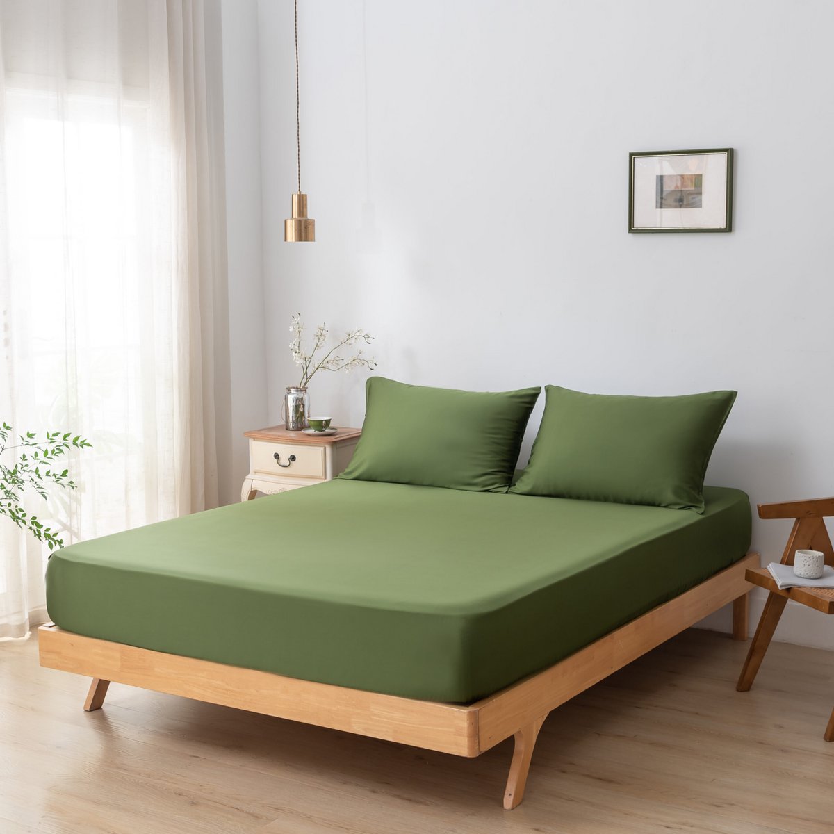 Deep Moss bamboo fitted sheet styled on a wood-frame bed in a sunlit bedroom.