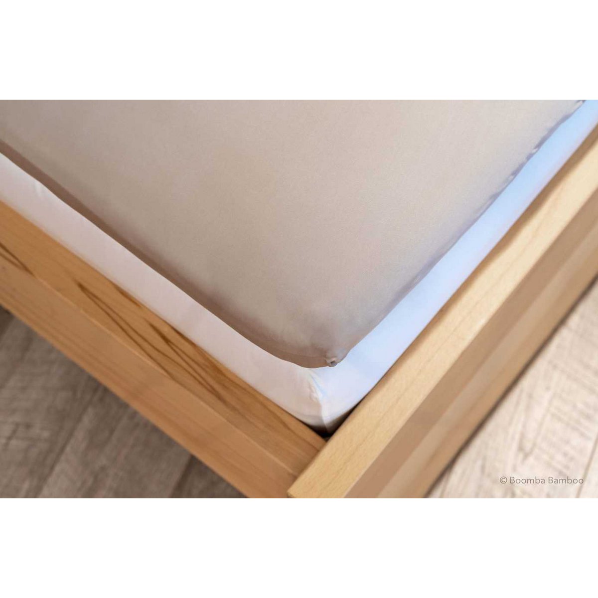 Soft Taupe bamboo fitted sheet for mattress toppers, showing its deep pocket fitted over a topper corner on a wood bed frame.