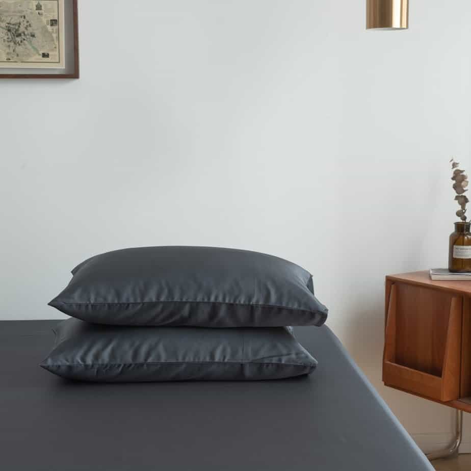 Space Blue bamboo pillowcases styled on a bench in a bedroom setting