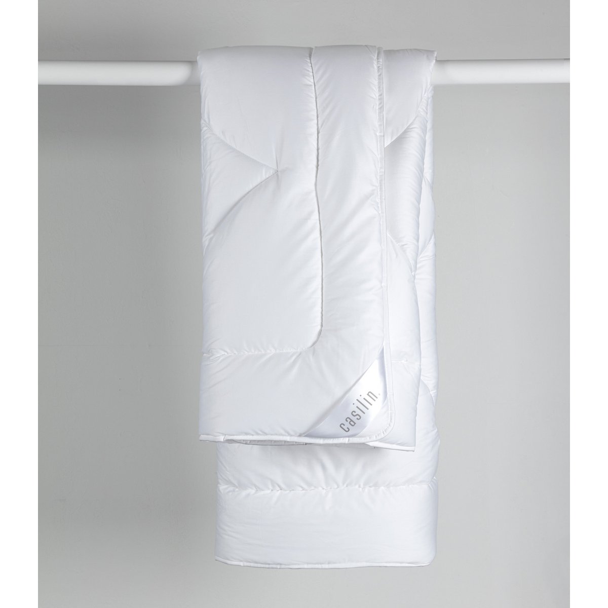 White Casilin Satin Mono duvet hanging folded, showing the sateen sheen and Casilin label