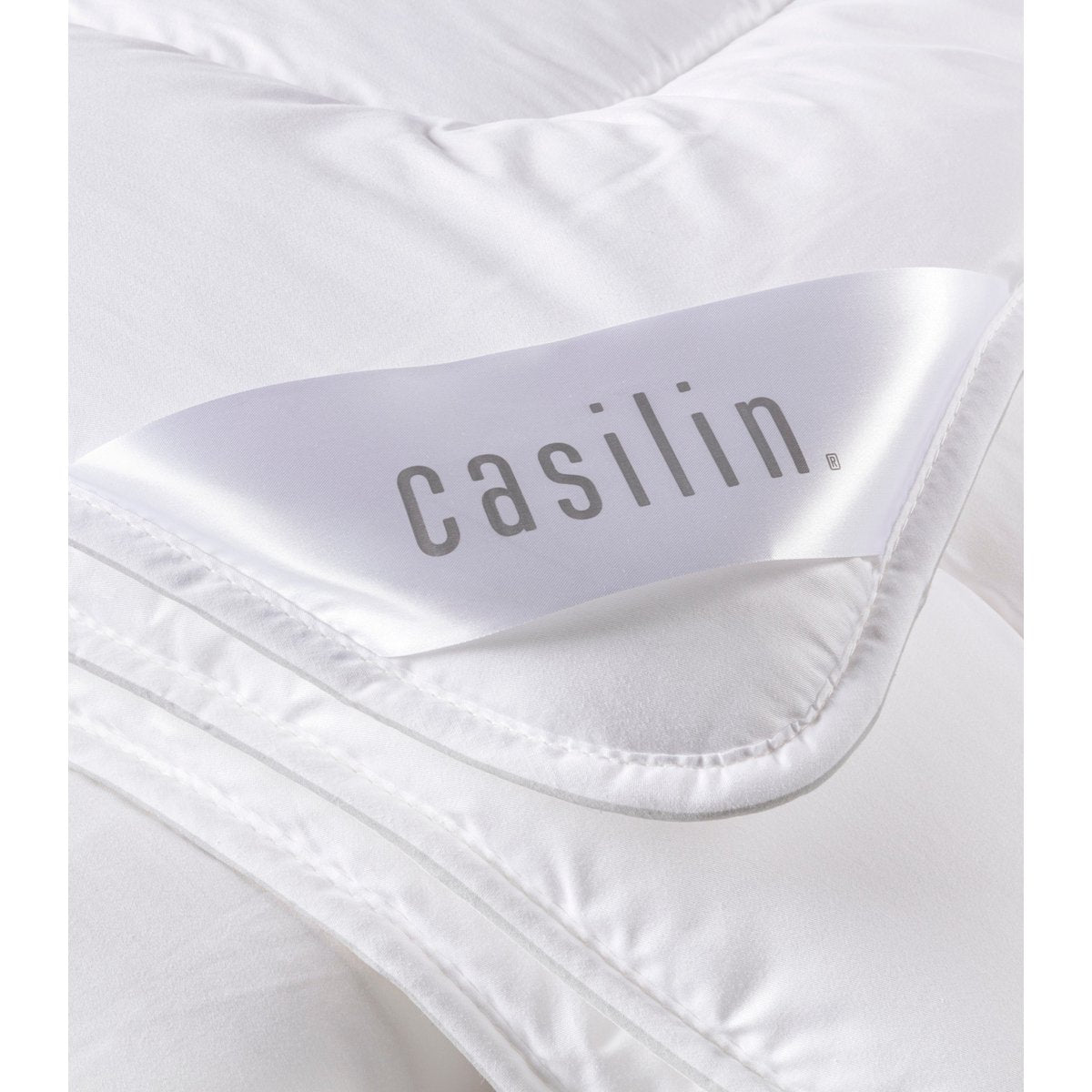 Close-up of the white cotton satin corner of the Satin Mono duvet with the Casilin label