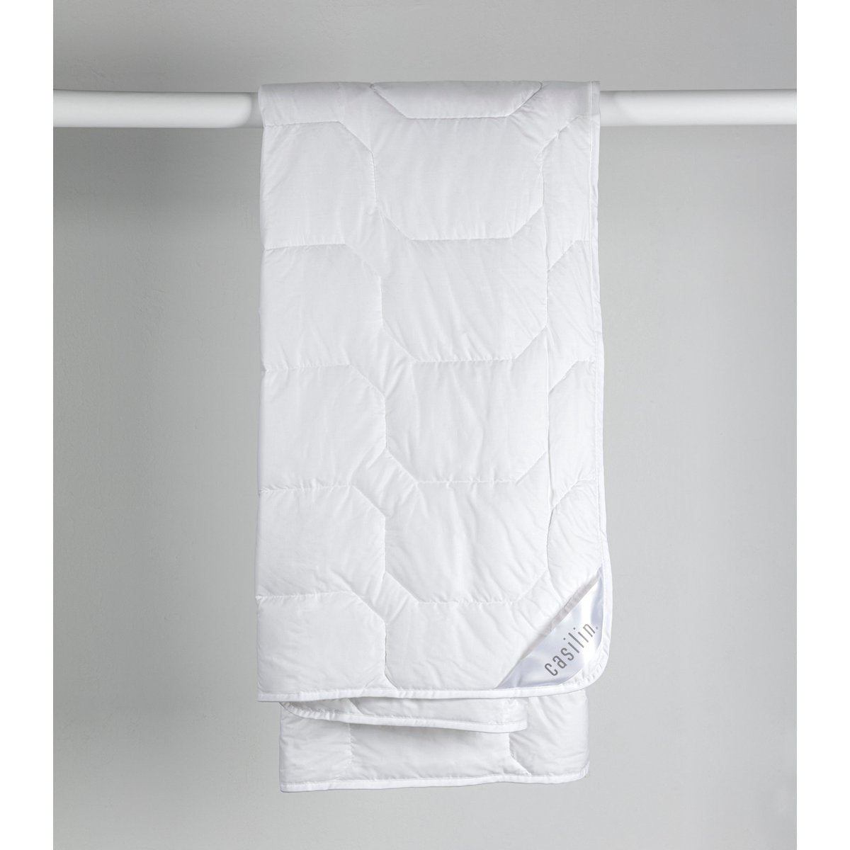 White Casilin Summer Cotton Light duvet hanging folded, showing the honeycomb quilted pattern and Casilin label