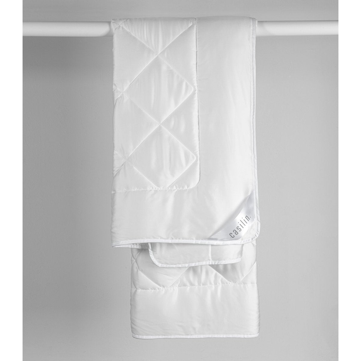 White Casilin Super Soft Light duvet hanging folded, showing diamond-quilted Tencel satin