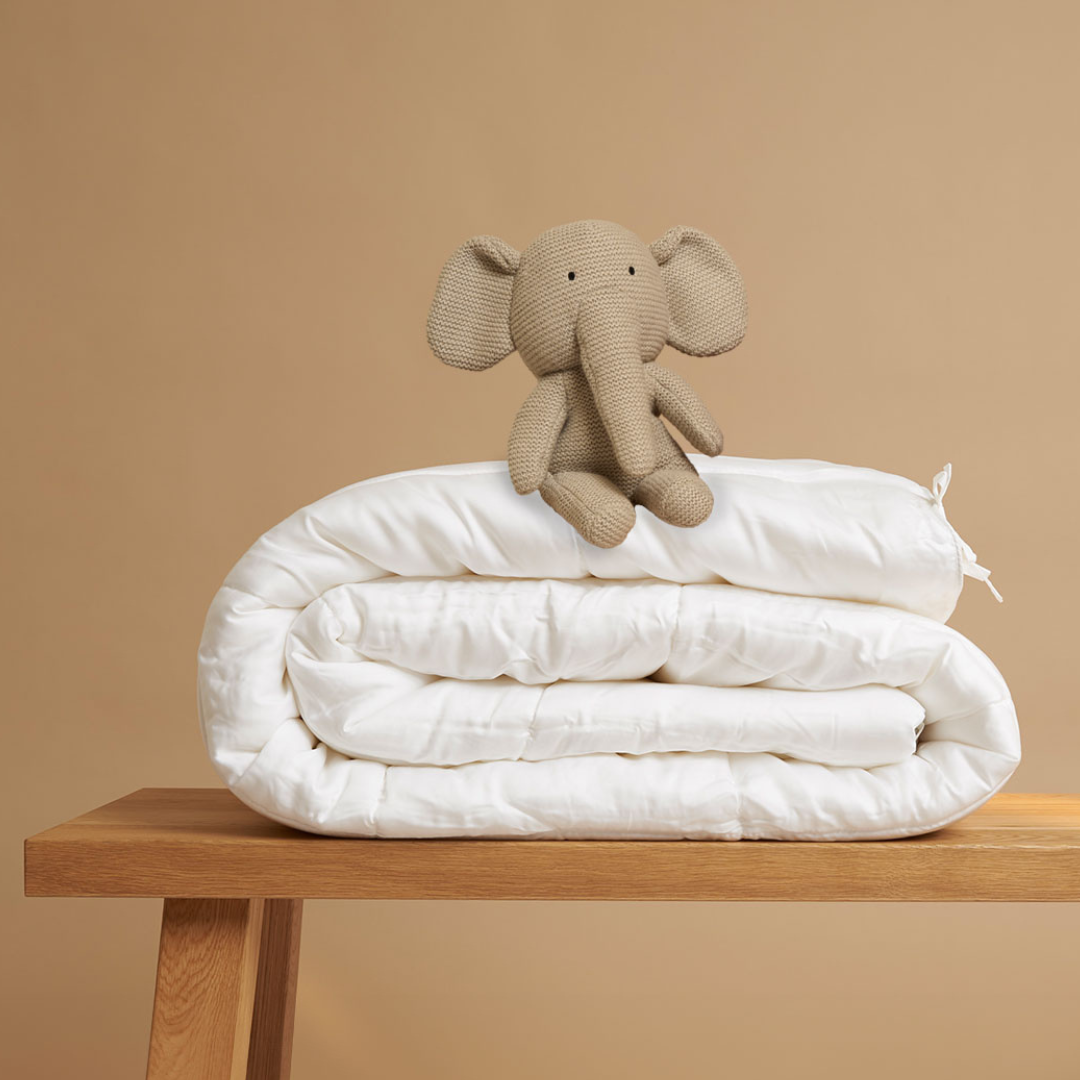 Tencel™ Four Seasons Duvet folded on a bench, styled with a plush elephant toy