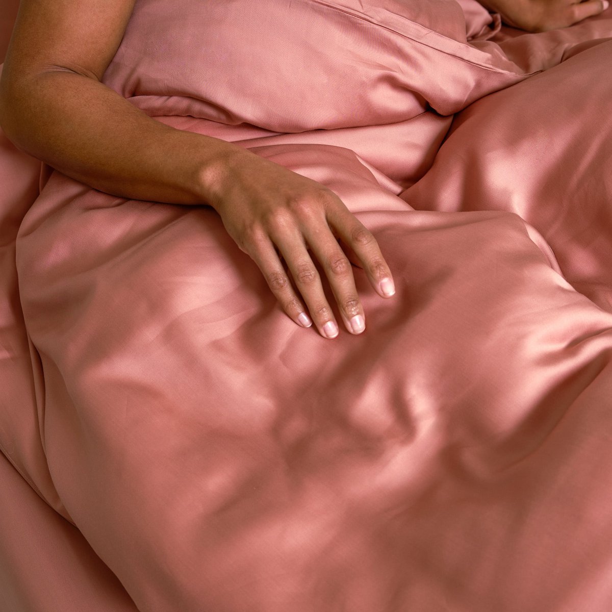 Hand resting on the Tencel™ Sateen Duvet Cover in Terra Pink