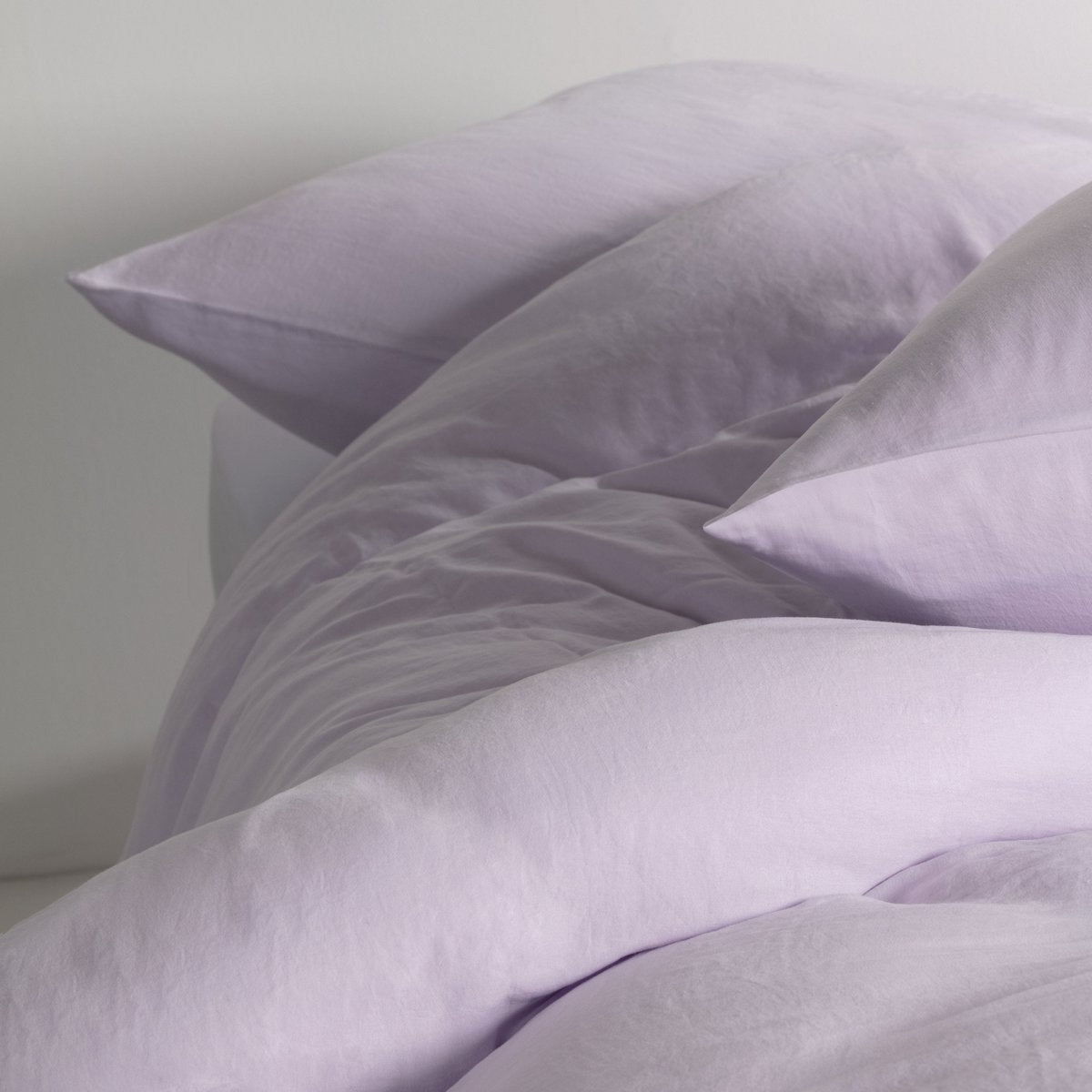 Close-up of pale lilac Tencel satin duvet cover and pillowcases showing the smooth fabric texture