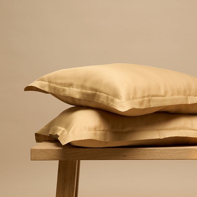 Tencel™ Twill Pillowcase in Ocher Yellow stacked on a wooden bench