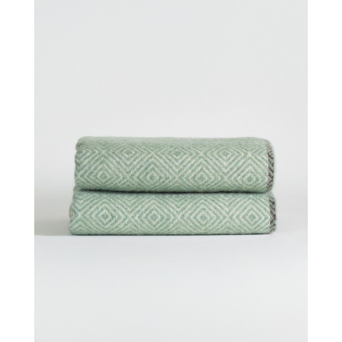 Two green textured towels stacked on a white background